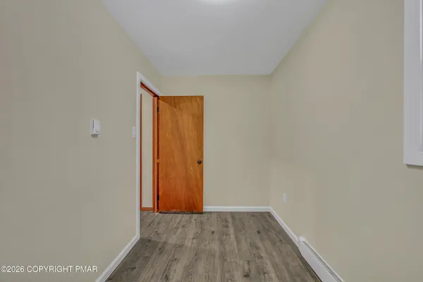 a view of an empty room with wooden floor and closet
