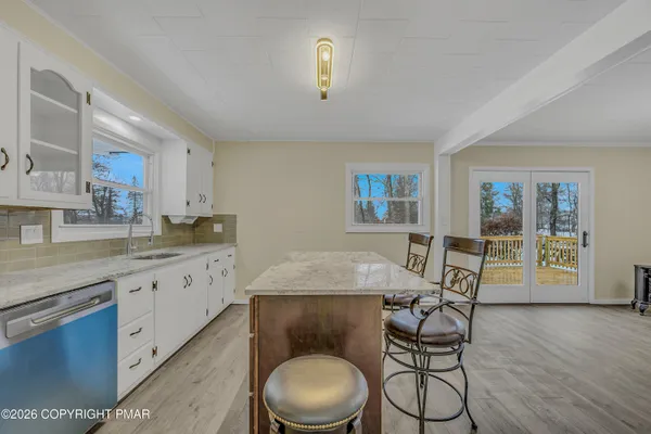 a kitchen with granite countertop a dining table chairs and white cabinets