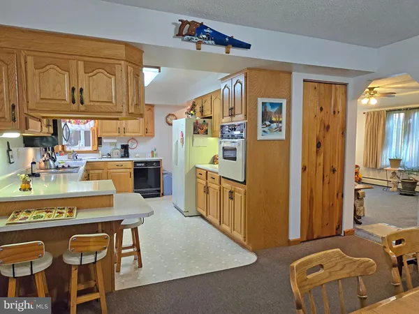 a kitchen with stainless steel appliances granite countertop a refrigerator a sink dishwasher a dining table and chairs with wooden floor