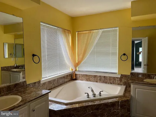 a bathroom with a granite countertop tub sink and mirror
