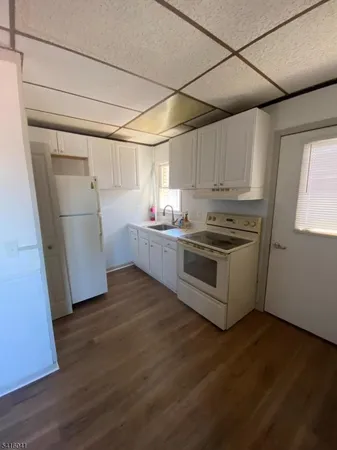 a kitchen with granite countertop white cabinets and white appliances