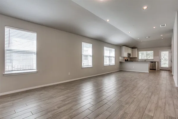 a view of empty room with wooden floor and windows