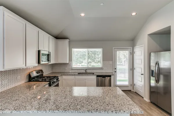 a kitchen with stainless steel appliances granite countertop a refrigerator sink and cabinets