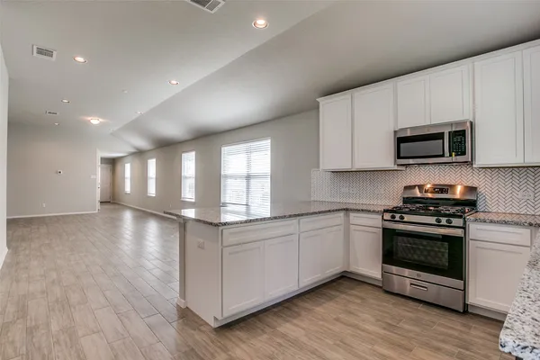 a kitchen with stainless steel appliances granite countertop a stove a sink and a microwave