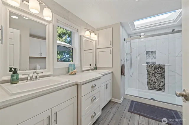 a spacious bathroom with double vanity a mirror and a shower
