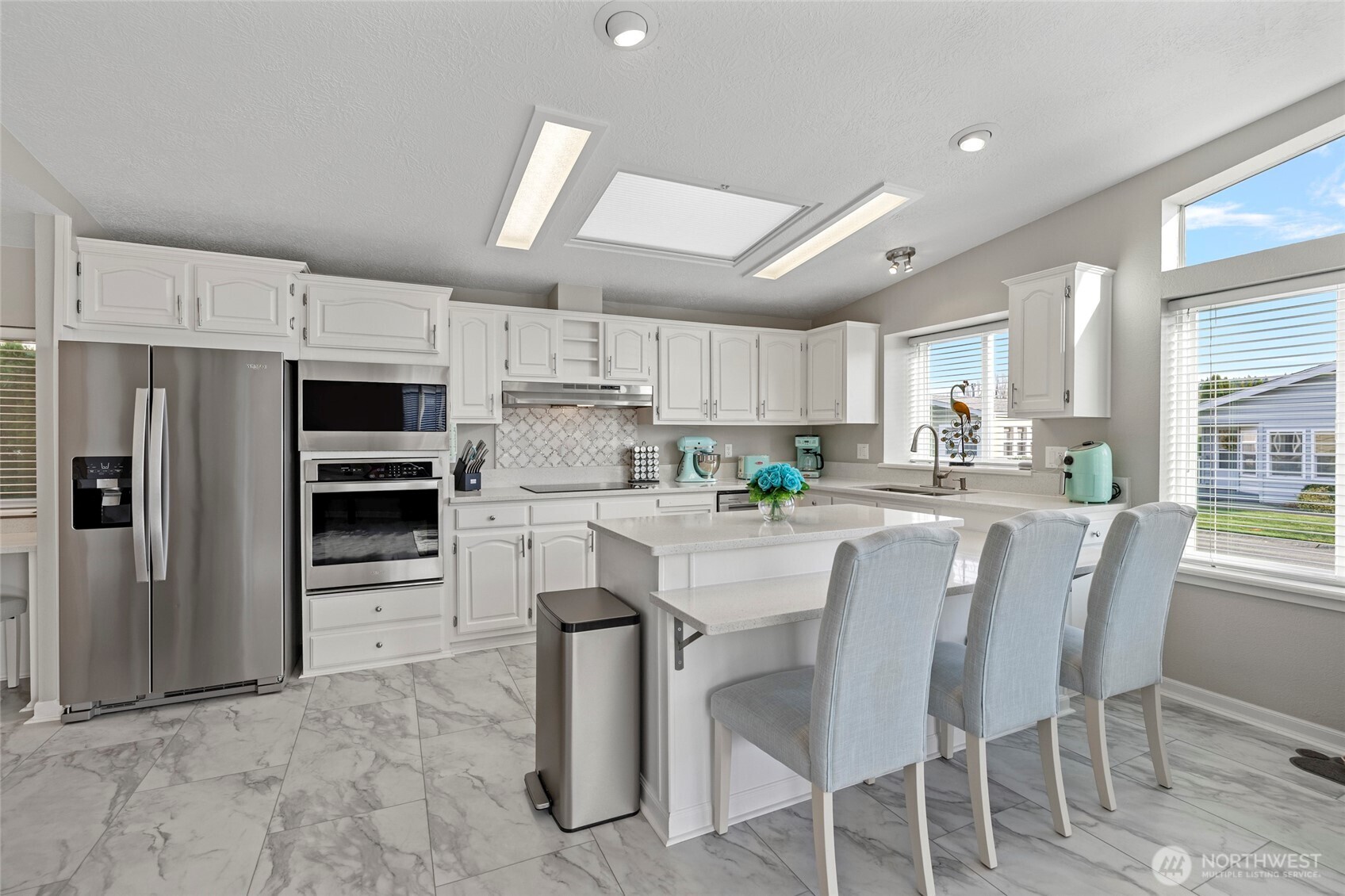 2610 East Section Street, Unit 12 Mount Vernon, WA 98274 - Photo 10 of 39 a kitchen with stainless steel appliances a refrigerator a stove a sink a dining table and chairs