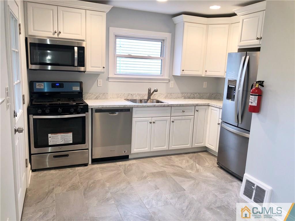 27 Forrest Street Iselin, NJ 08830 - Photo 2 of 12 a kitchen with stainless steel appliances a stove microwave and refrigerator