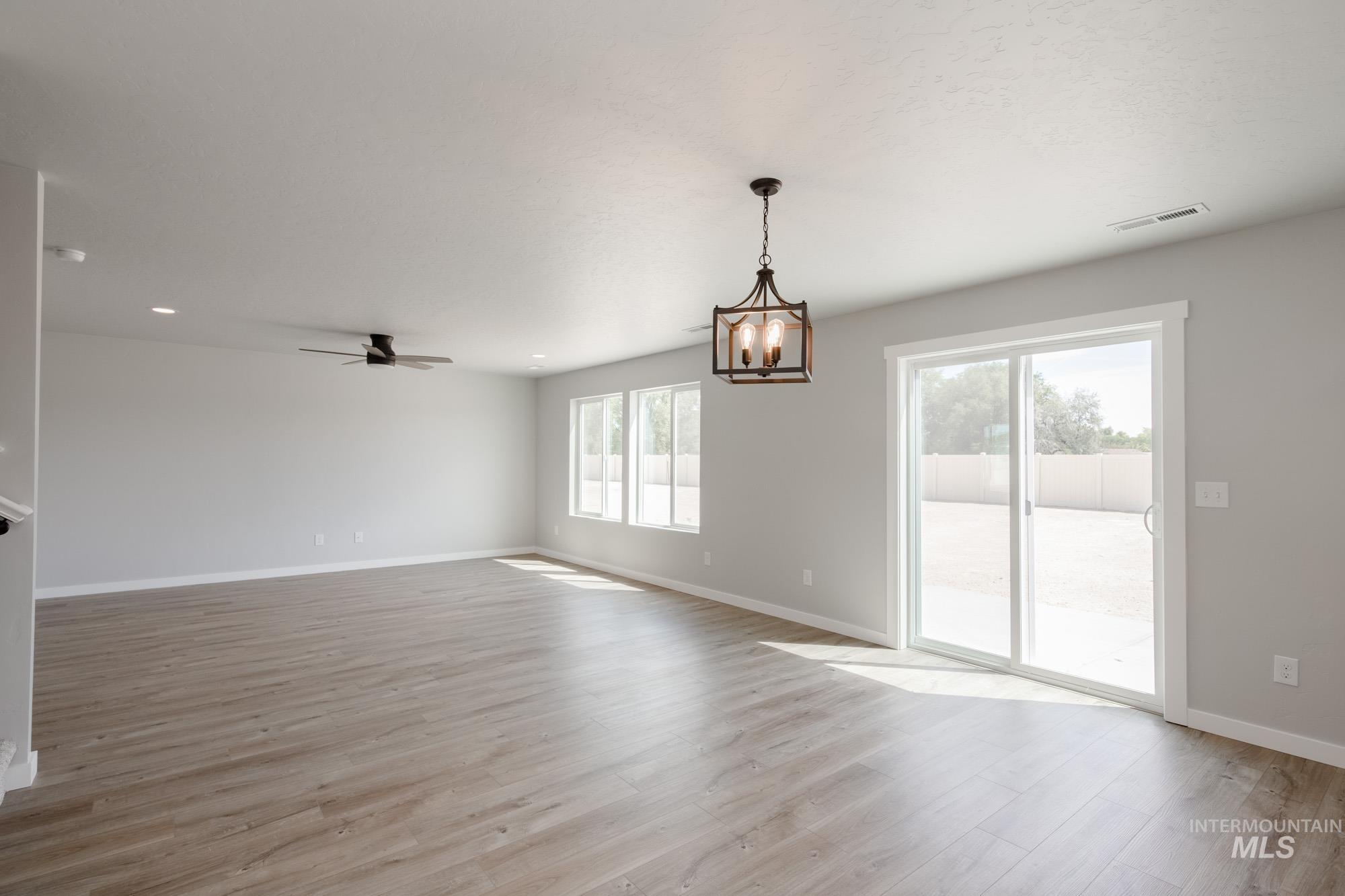5328 Castleton Avenue Nampa, ID 83686 - Photo 11 of 26 Empty room featuring light wood-type flooring, a ceiling fan, and a chandelier