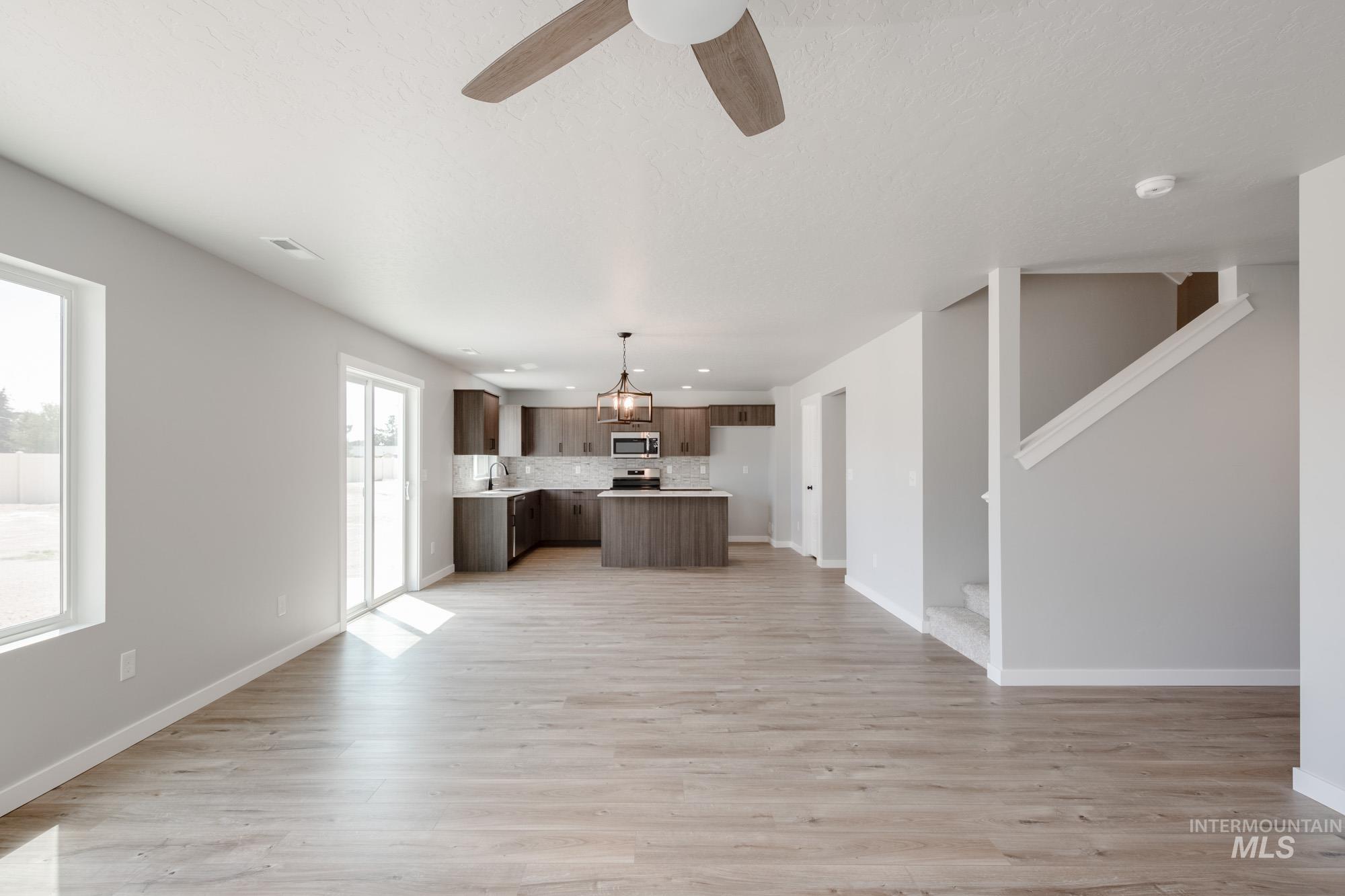 5328 Castleton Avenue Nampa, ID 83686 - Photo 13 of 26 Unfurnished living room with light wood finished floors, stairs, and ceiling fan