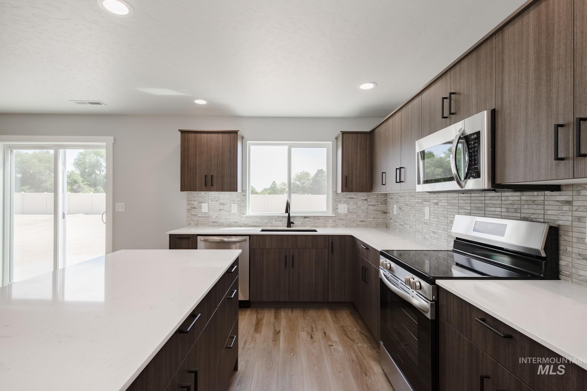 5328 Castleton Avenue Nampa, ID 83686 - Photo 5 of 26 Kitchen with appliances with stainless steel finishes, light countertops, light wood-style flooring, decorative backsplash, and recessed lighting