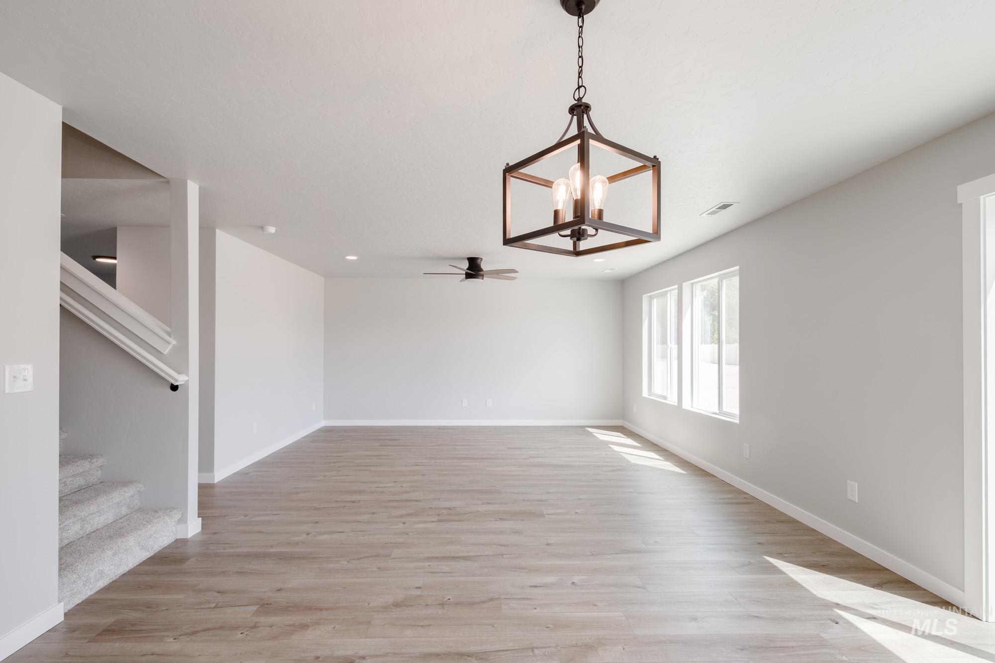 5328 Castleton Avenue Nampa, ID 83686 - Photo 8 of 26 Unfurnished dining area featuring light wood-style floors, ceiling fan, stairs, and a chandelier