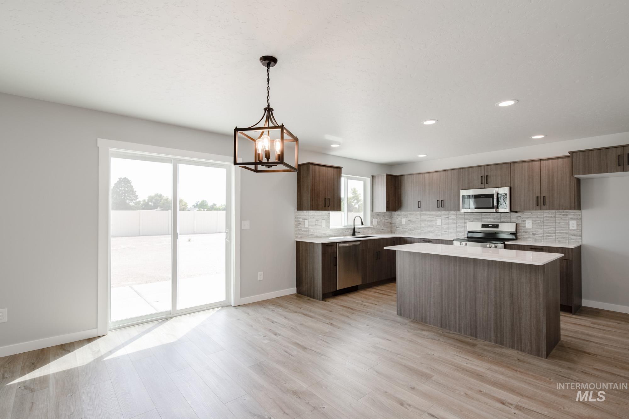 5328 Castleton Avenue Nampa, ID 83686 - Photo 9 of 26 Kitchen featuring backsplash, light countertops, a chandelier, a kitchen island, and stainless steel appliances