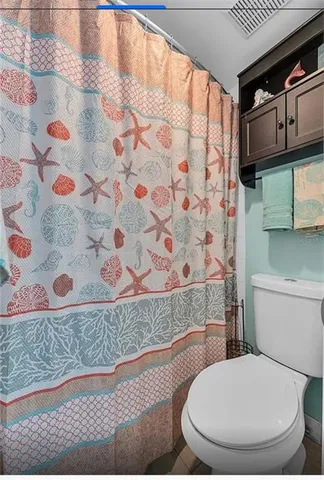 a white toilet sitting next to a shower curtain