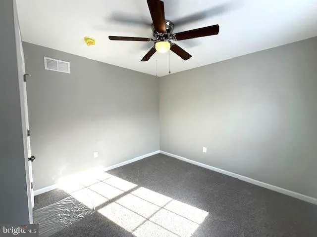an empty room with a ceiling fan and carpet
