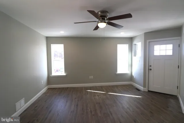 an empty room with wooden floor and windows