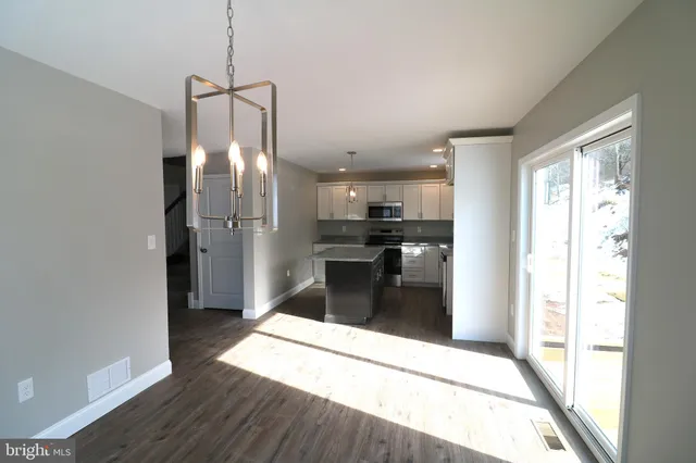 a kitchen with stainless steel appliances a refrigerator and a wooden floor