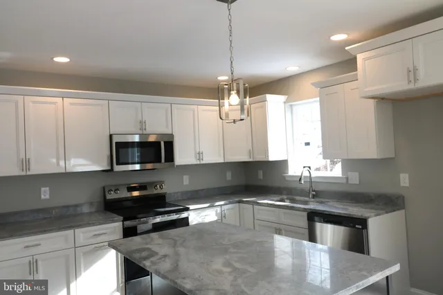 a kitchen with kitchen island granite countertop a sink counter space appliances and cabinets