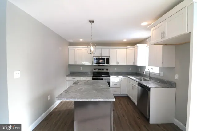 a large kitchen with a center island wooden floor and stainless steel appliances