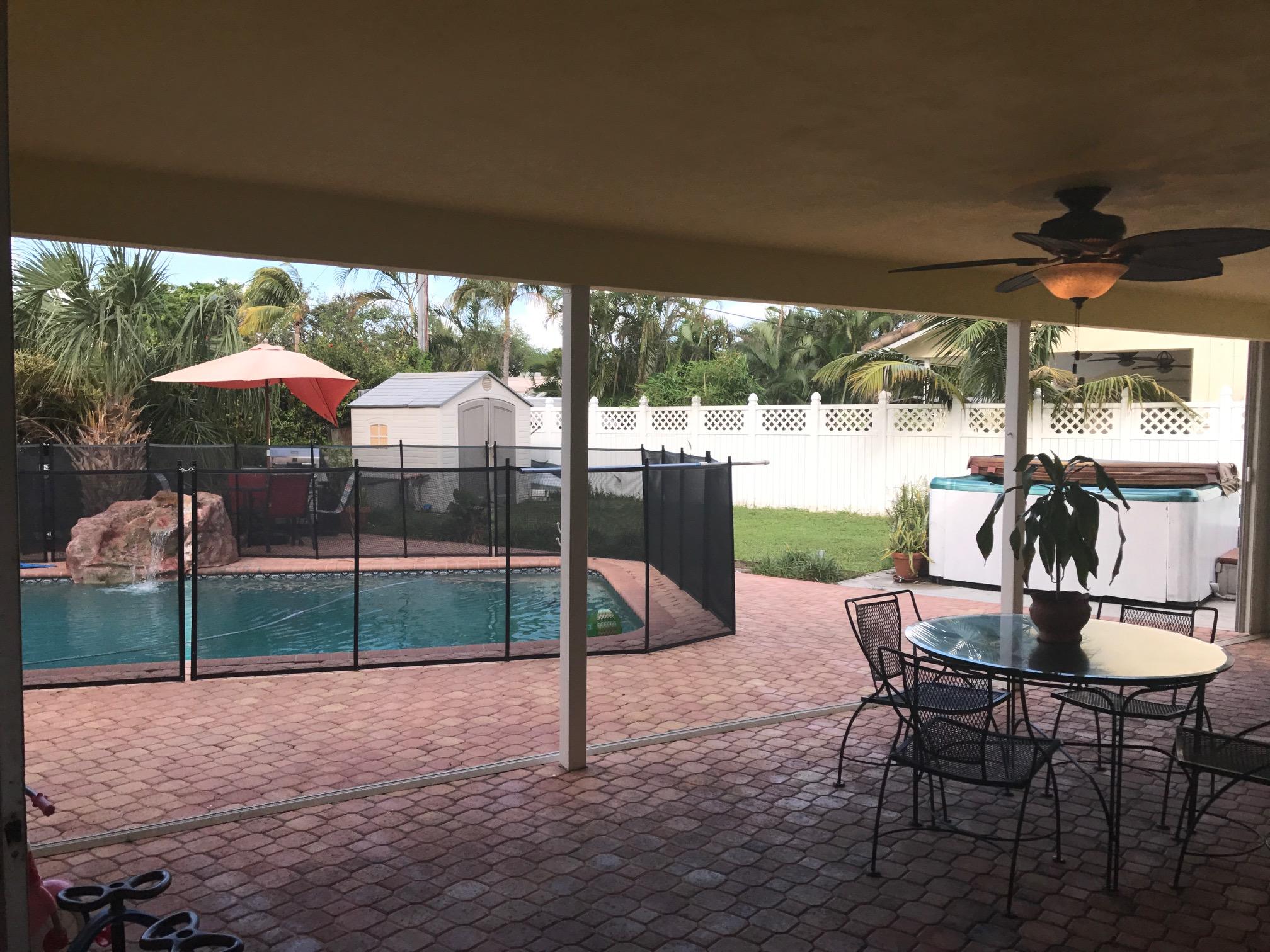 1299 Southwest 4th Street Boca Raton, FL 33486 - Photo 9 of 34 a view of a yard with a table and chairs under an umbrella