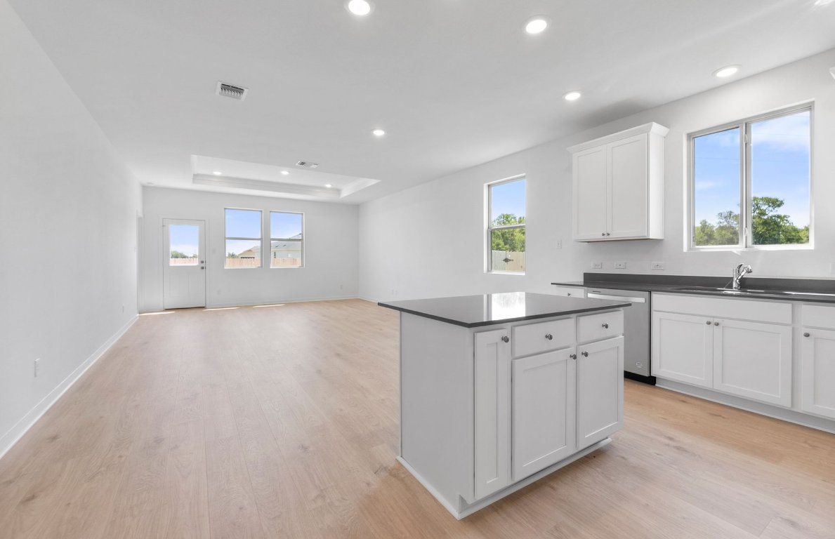 1016 Kerr Court Temple, TX 76501 - Photo 4 of 15 a kitchen with granite countertop a stove a sink and white cabinets with wooden floor