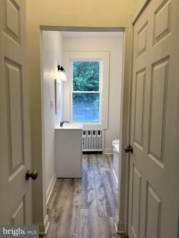 a view of a hallway with wooden floor and a bathroom