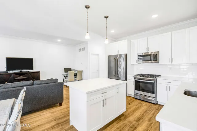 a kitchen with stainless steel appliances a stove a sink a microwave a refrigerator a stove and white cabinets