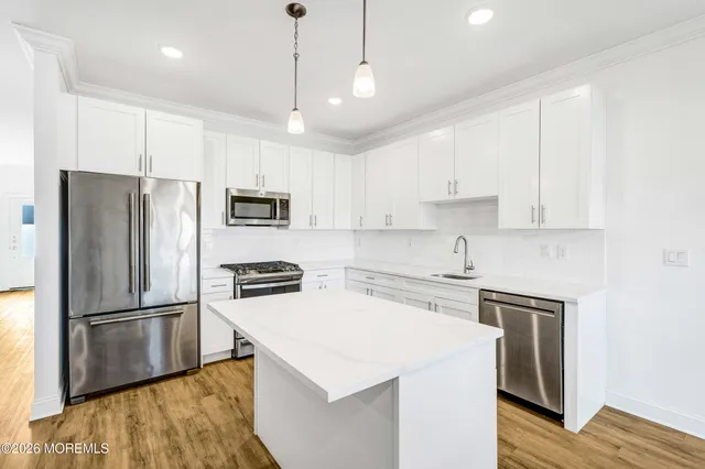 a kitchen with cabinets stainless steel appliances and wooden floor