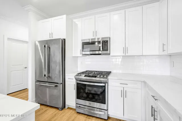 a kitchen with stainless steel appliances white cabinets and a stove a refrigerator with wooden floor