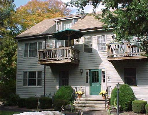 55 Village Walk, Unit 55 Wilton, CT 06897 - Photo 1 of 1 a view of a white house with large windows and a table and chairs