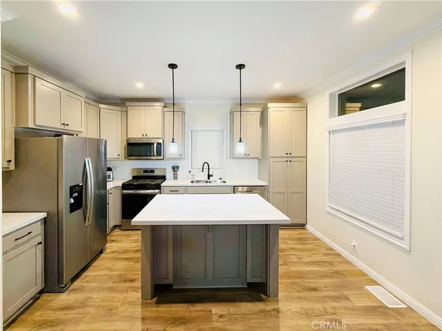 a large kitchen with kitchen island a stove a refrigerator a sink dishwasher and a refrigerator with wooden floor