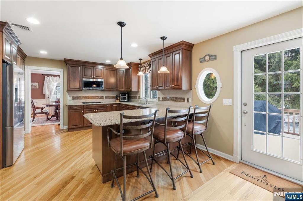 4 Lindeman Avenue Closter, NJ 07624 - Photo 16 of 36 a kitchen with stainless steel appliances kitchen island granite countertop a refrigerator a stove a microwave oven a sink with a dining table and chairs with wooden floor