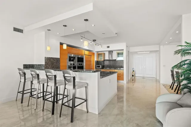 a kitchen with stainless steel appliances kitchen island granite countertop a table and chairs