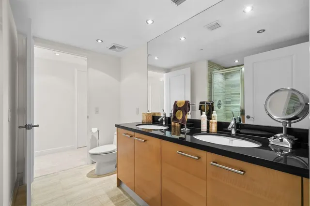 a bathroom with a double vanity sink a toilet and a mirror