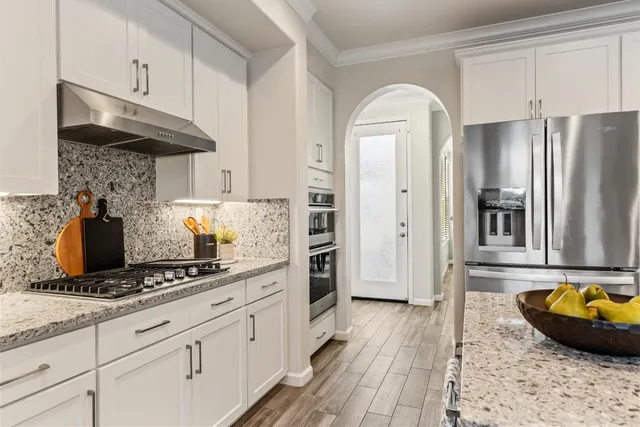 a large kitchen with kitchen island a large counter top stainless steel appliances and cabinets