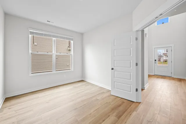 a view of an empty room with window and wooden floor