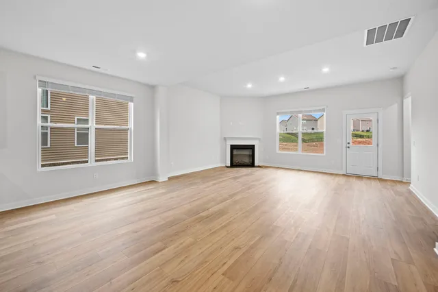 a view of empty room with wooden floor and windows