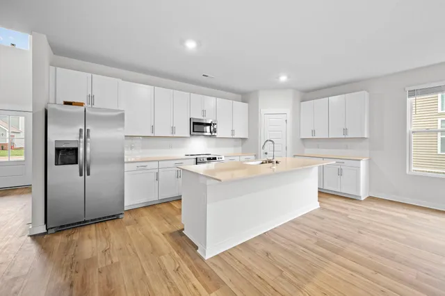 a large kitchen with cabinets wooden floor and stainless steel appliances