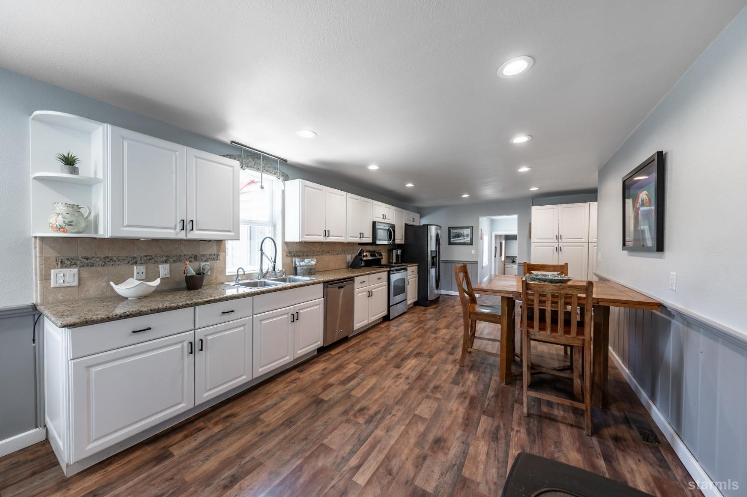 15740 Highway 89 Markleeville, CA 96120 - Photo 7 of 24 a kitchen with stainless steel appliances kitchen island granite countertop white cabinets a sink a stove a dining table and chairs