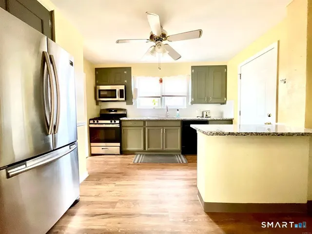 a kitchen with stainless steel appliances granite countertop a refrigerator a stove and a sink