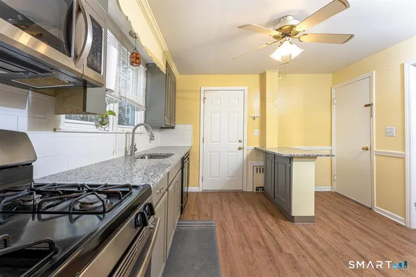 a kitchen with stainless steel appliances granite countertop a stove a sink and a microwave