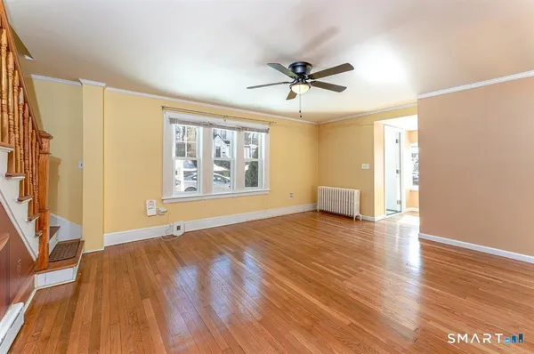 a view of an empty room with a window and wooden floor