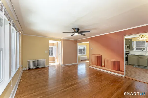a view of an empty room with window and wooden floor