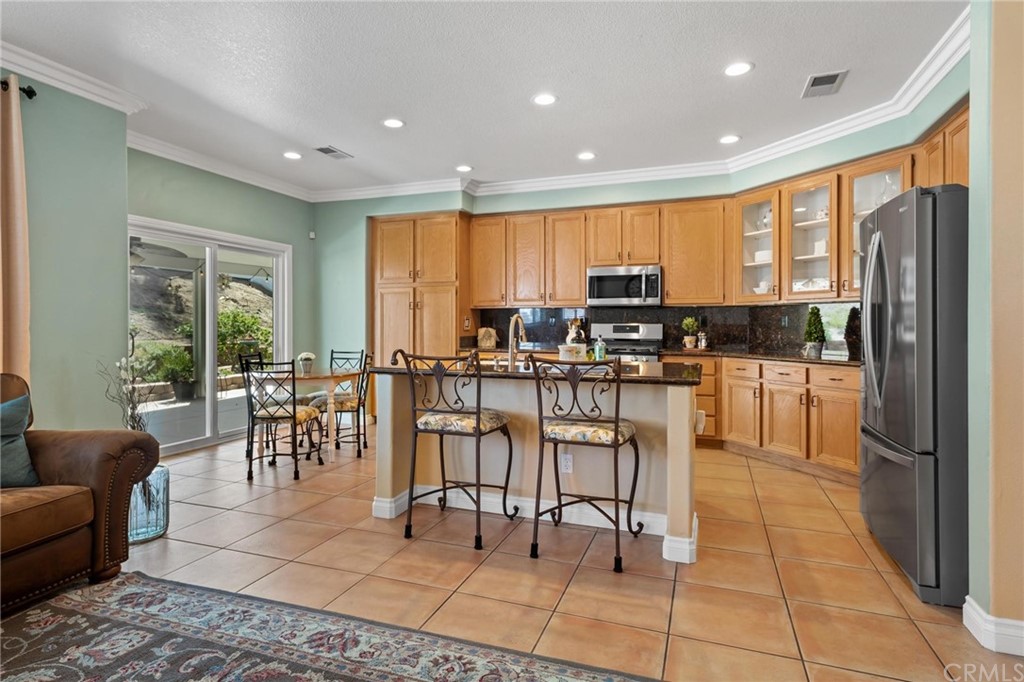 20803 Millbrook Street Riverside, CA 92508 - Photo 12 of 44 a kitchen with stainless steel appliances dining table a refrigerator and cabinets