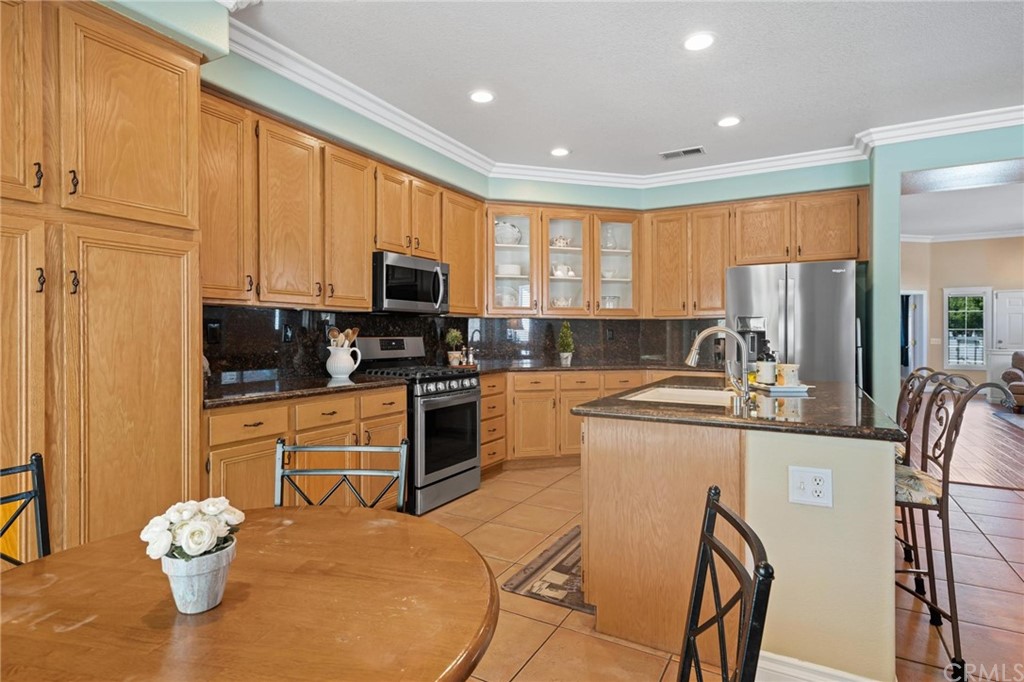 20803 Millbrook Street Riverside, CA 92508 - Photo 16 of 44 a kitchen with stainless steel appliances granite countertop a refrigerator a stove top oven a sink dishwasher and white cabinets with wooden floor