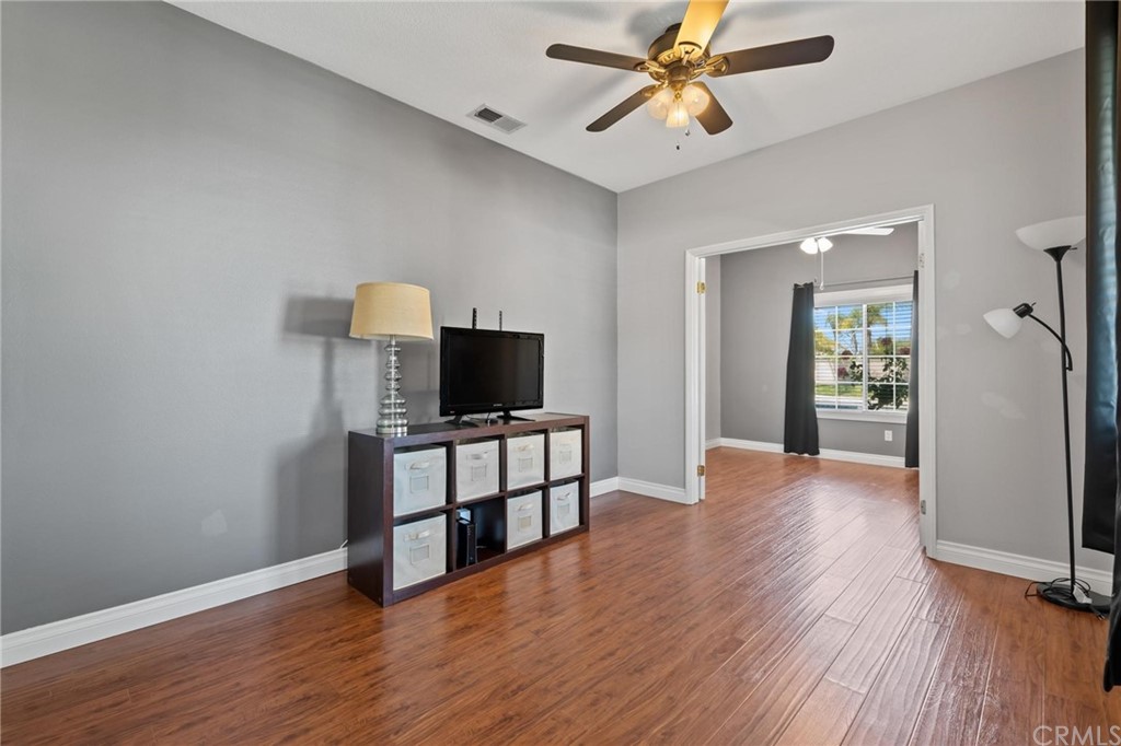 20803 Millbrook Street Riverside, CA 92508 - Photo 6 of 44 a view of a livingroom with a flat screen tv wooden floor and a ceiling fan