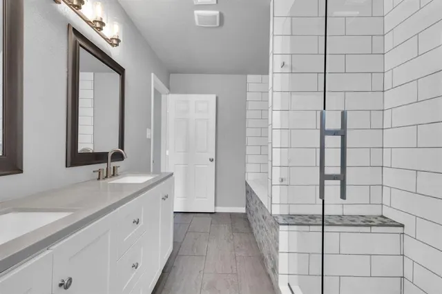 a spacious bathroom with a double vanity sink a mirror and shower