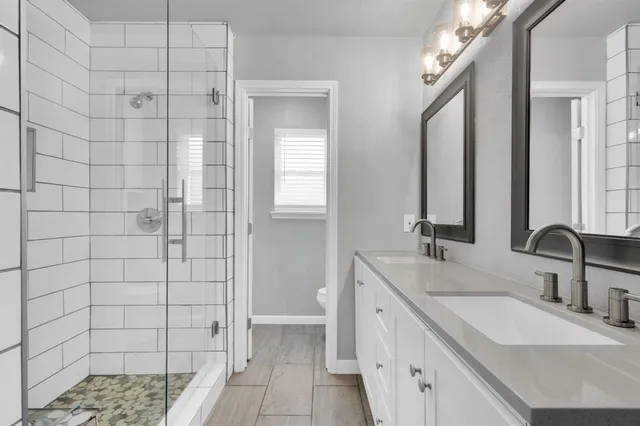a bathroom with a double sink shower and a mirror