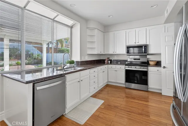 a dining hall with stainless steel appliances white cabinets and wooden floor