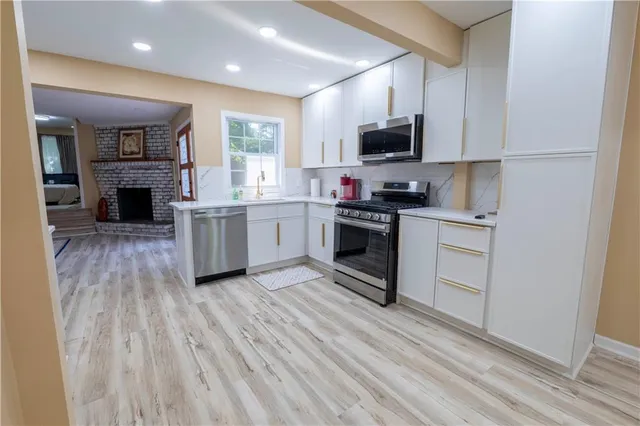 a kitchen with stainless steel appliances granite countertop a stove top oven a sink dishwasher and a refrigerator with wooden floor