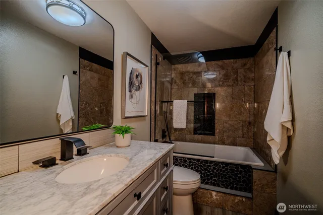 a bathroom with a granite countertop sink a toilet and shower